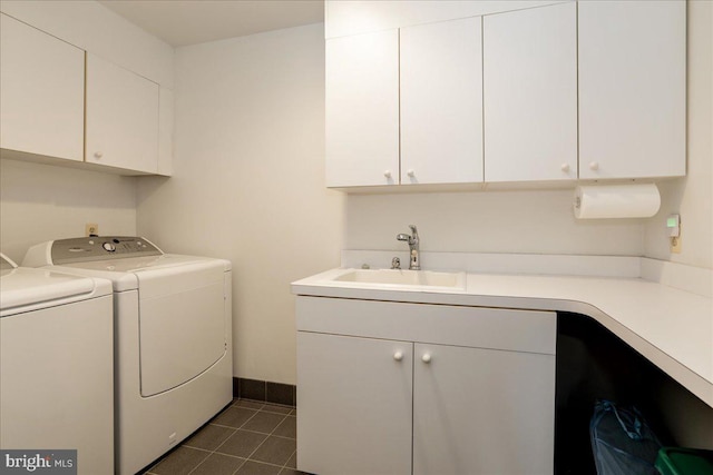 washroom with sink, washing machine and dryer, cabinets, and dark tile patterned flooring