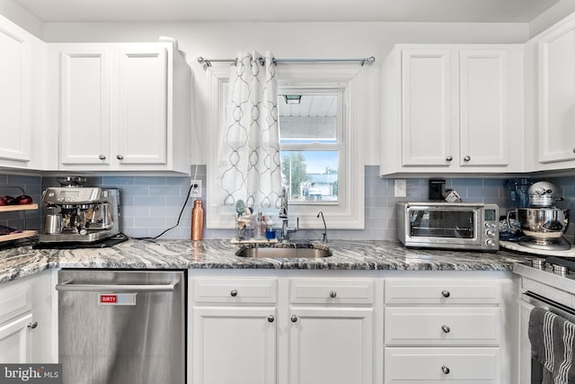 kitchen with a sink, stone counters, white cabinetry, and dishwasher