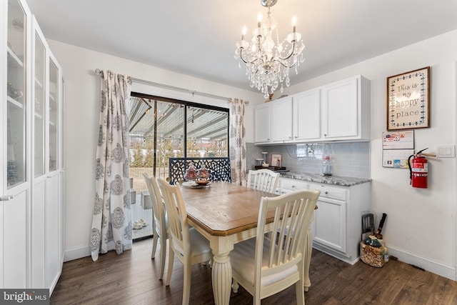 dining room featuring dark wood-style floors, a notable chandelier, and baseboards