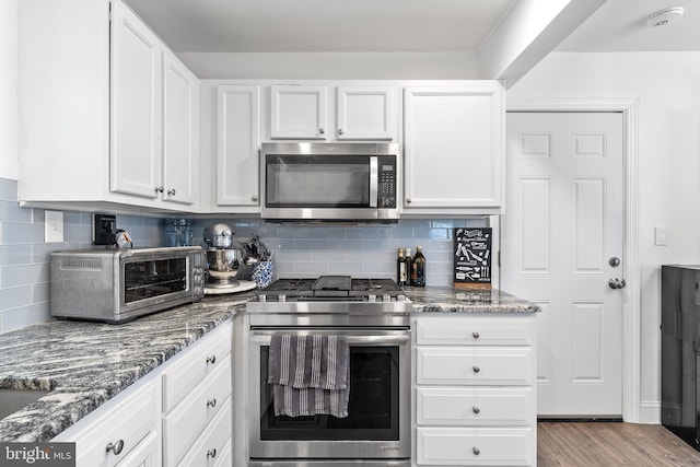 kitchen with light wood-type flooring, a toaster, appliances with stainless steel finishes, and white cabinets