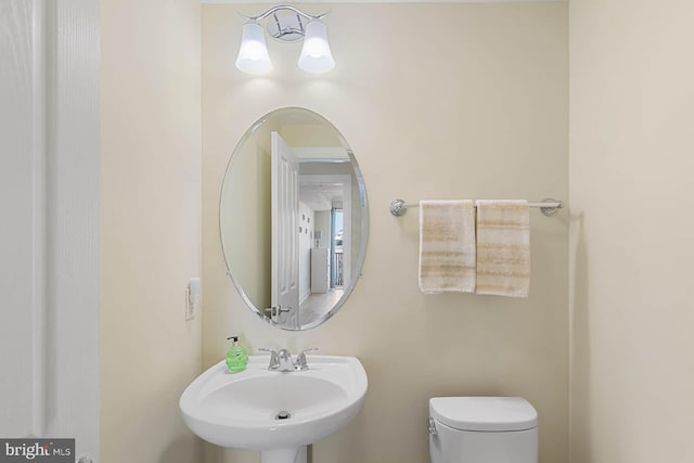 bathroom featuring sink, a notable chandelier, and toilet