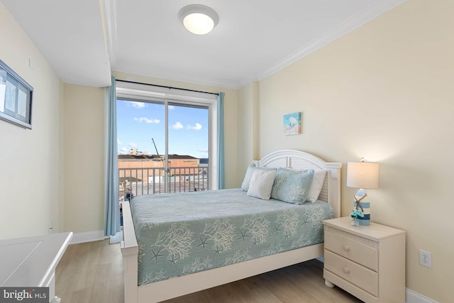 bedroom with hardwood / wood-style floors, access to outside, and ornamental molding