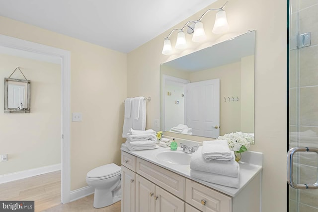 bathroom with an enclosed shower, vanity, hardwood / wood-style floors, and toilet