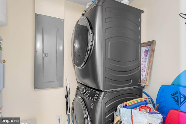 clothes washing area with electric panel and stacked washer and clothes dryer