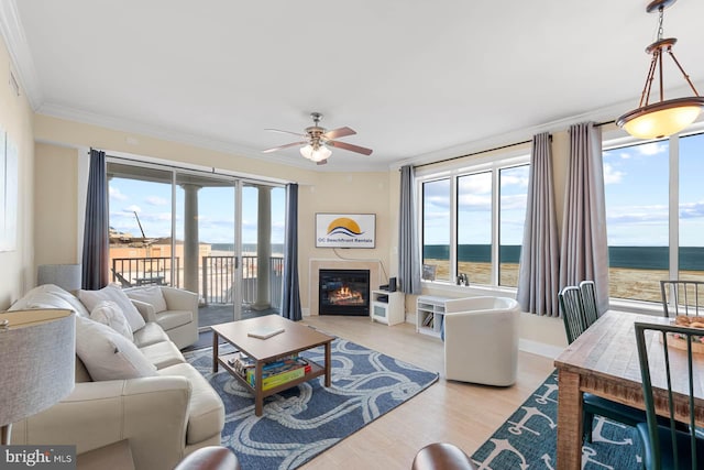 living room featuring crown molding, light hardwood / wood-style flooring, ceiling fan, and a water view