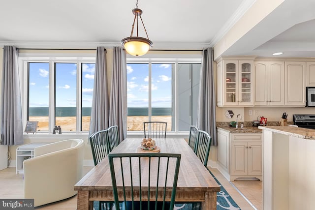 tiled dining space featuring a water view and crown molding