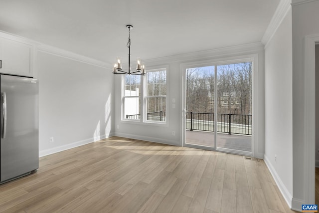 unfurnished dining area featuring an inviting chandelier, crown molding, and light hardwood / wood-style floors