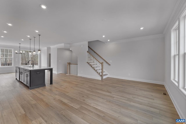 kitchen with sink, gray cabinetry, a center island with sink, pendant lighting, and light hardwood / wood-style floors