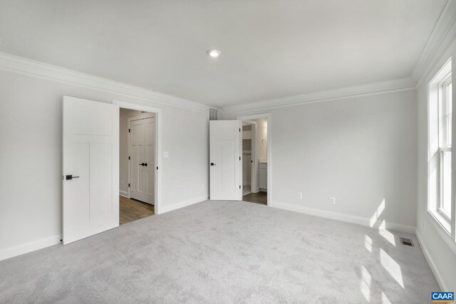 carpeted empty room with a wealth of natural light and ornamental molding