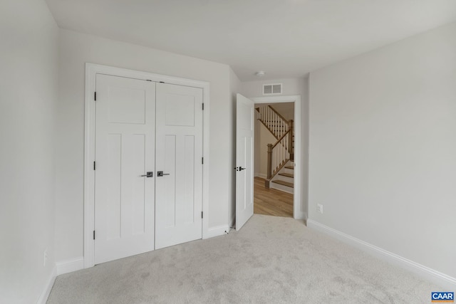 unfurnished bedroom with light colored carpet and a closet