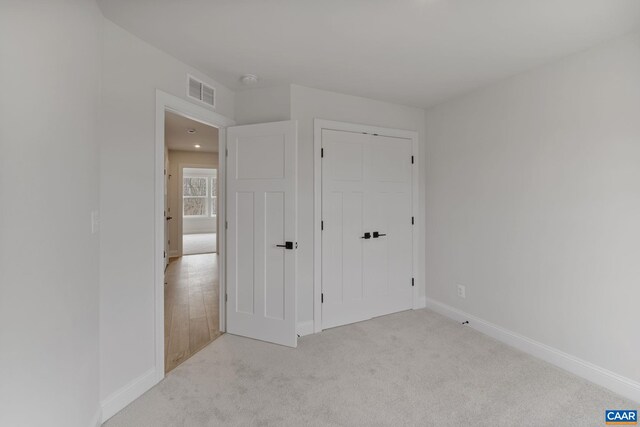 unfurnished bedroom featuring light colored carpet and a closet