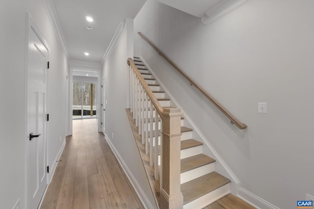 staircase with ornamental molding and hardwood / wood-style floors