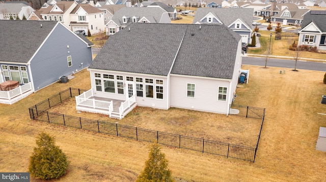 rear view of house with a fenced backyard, a residential view, a lawn, and roof with shingles