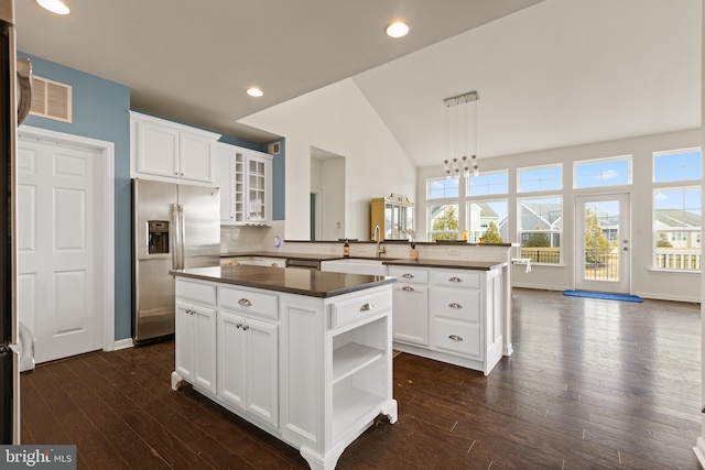 kitchen with white cabinetry, a center island, kitchen peninsula, and stainless steel fridge with ice dispenser