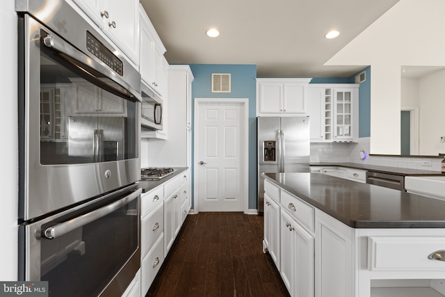 kitchen with sink, appliances with stainless steel finishes, white cabinetry, dark hardwood / wood-style flooring, and decorative backsplash