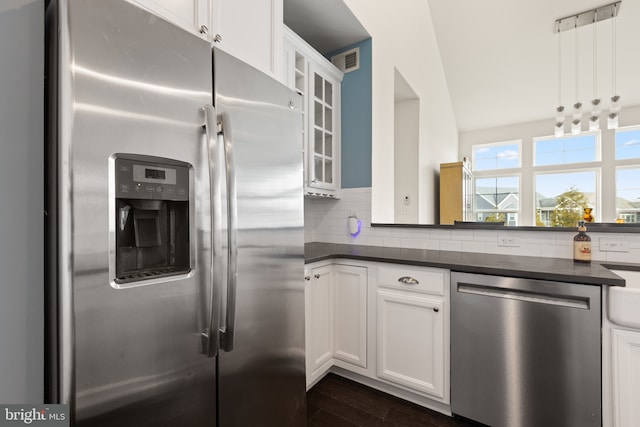 kitchen featuring visible vents, dark countertops, glass insert cabinets, stainless steel appliances, and backsplash