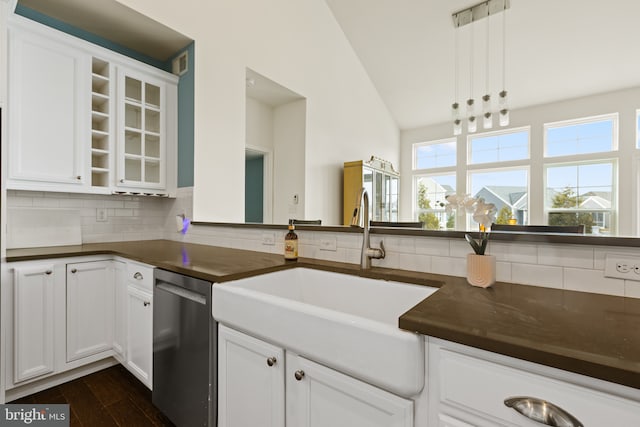 kitchen with dark countertops, decorative backsplash, white cabinetry, a sink, and dishwasher