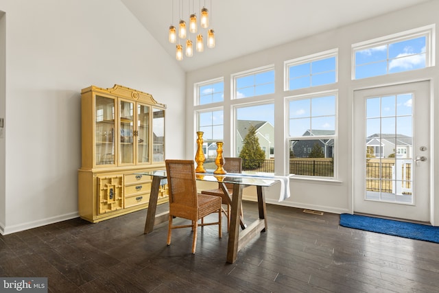 dining area with high vaulted ceiling, dark hardwood / wood-style floors, and a chandelier