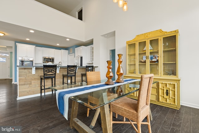 dining area with a towering ceiling, baseboards, dark wood-type flooring, and recessed lighting