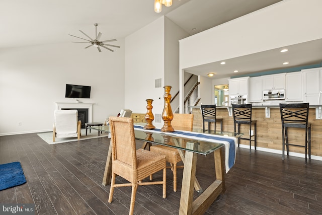 dining area with dark wood-style floors, a fireplace with flush hearth, stairs, and visible vents