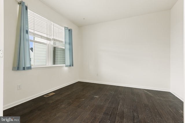 spare room featuring baseboards, visible vents, and dark wood-type flooring