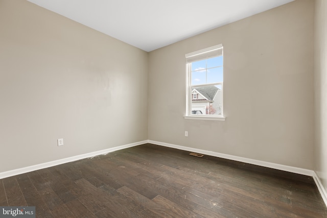 spare room featuring visible vents, dark wood finished floors, and baseboards