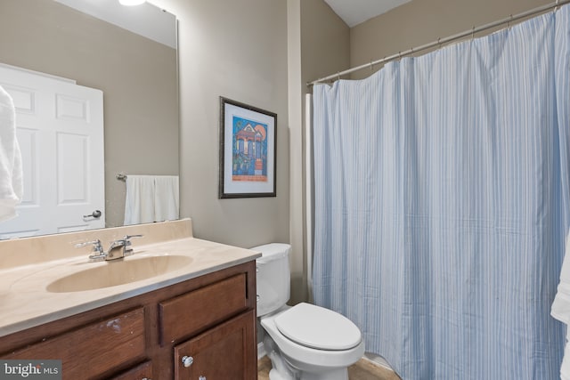 bathroom with curtained shower, vanity, and toilet