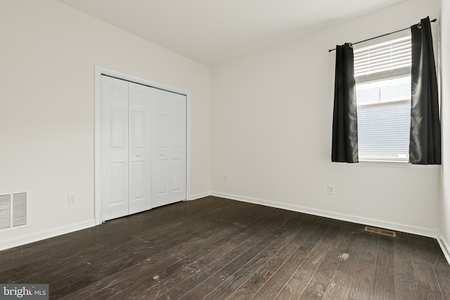 unfurnished bedroom with dark hardwood / wood-style flooring and a closet