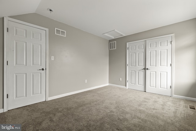 unfurnished bedroom featuring carpet floors, a closet, and vaulted ceiling