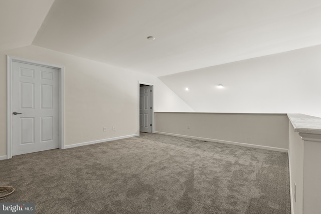 interior space with vaulted ceiling, carpet, and baseboards