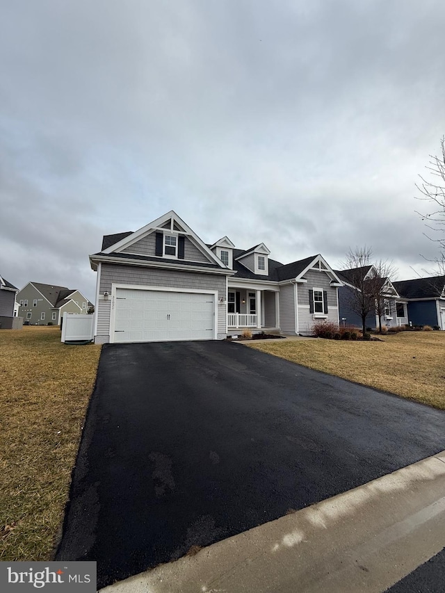 ranch-style home featuring a garage, covered porch, and a front lawn