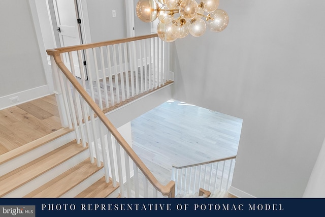 stairs featuring baseboards, wood finished floors, and a chandelier