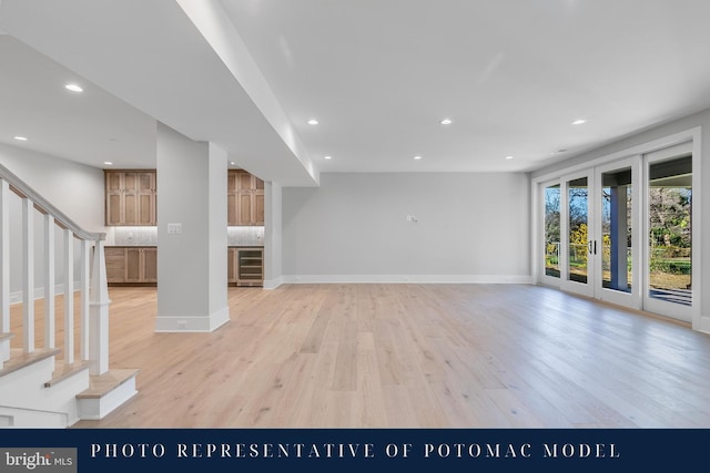 unfurnished living room featuring light wood finished floors, stairs, wine cooler, and recessed lighting