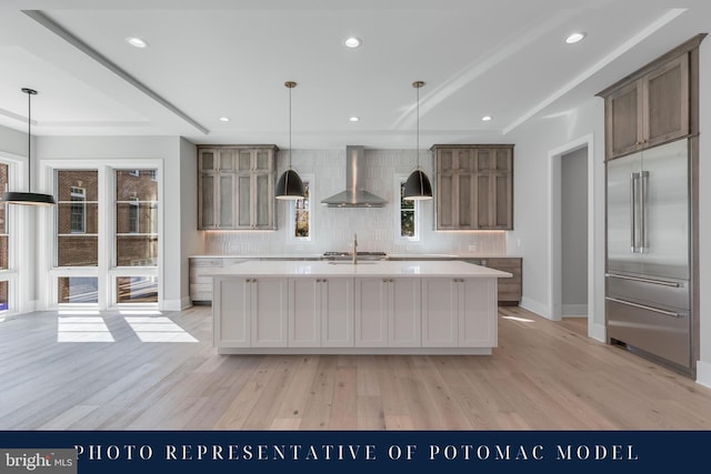 kitchen with light countertops, tasteful backsplash, and wall chimney exhaust hood