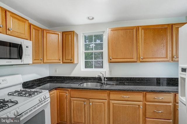 kitchen featuring dark stone counters, sink, and white range with gas stovetop