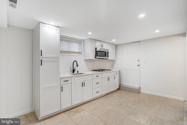 kitchen with tasteful backsplash, appliances with stainless steel finishes, sink, and white cabinets