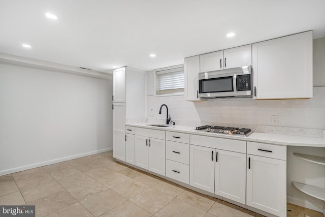 kitchen with appliances with stainless steel finishes, sink, white cabinets, and backsplash