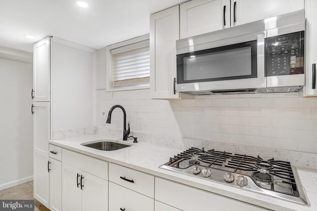 kitchen featuring sink, stainless steel appliances, light stone countertops, decorative backsplash, and white cabinets