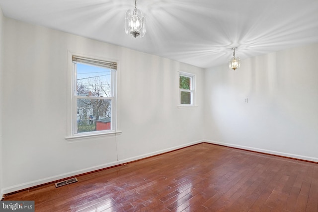 unfurnished room with hardwood / wood-style flooring and a chandelier