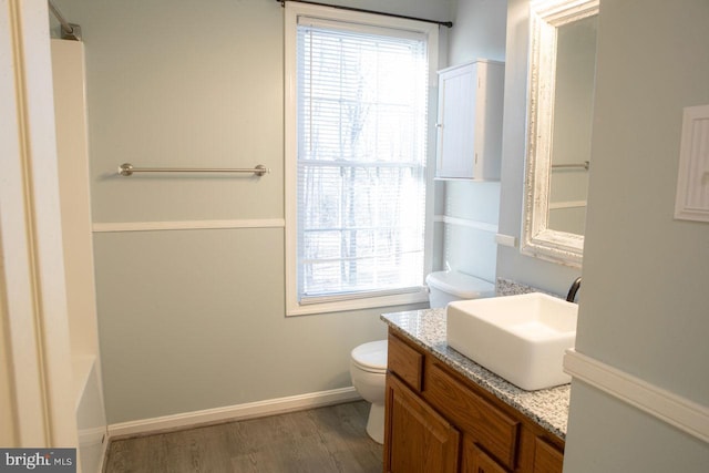 bathroom featuring vanity, hardwood / wood-style flooring, a tub, and toilet