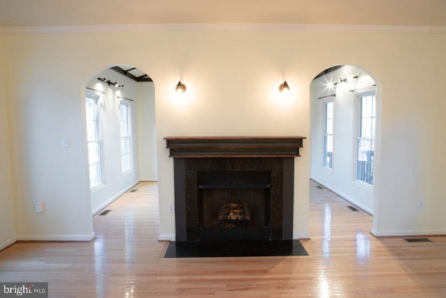 unfurnished living room featuring crown molding, a wealth of natural light, and light hardwood / wood-style floors