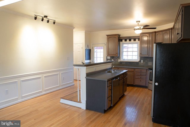 kitchen with appliances with stainless steel finishes, sink, decorative backsplash, a center island, and light wood-type flooring