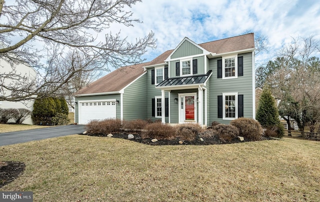 traditional home with a standing seam roof, aphalt driveway, board and batten siding, a front yard, and a garage