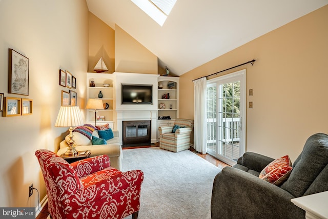 living room featuring a skylight, a fireplace with flush hearth, and high vaulted ceiling