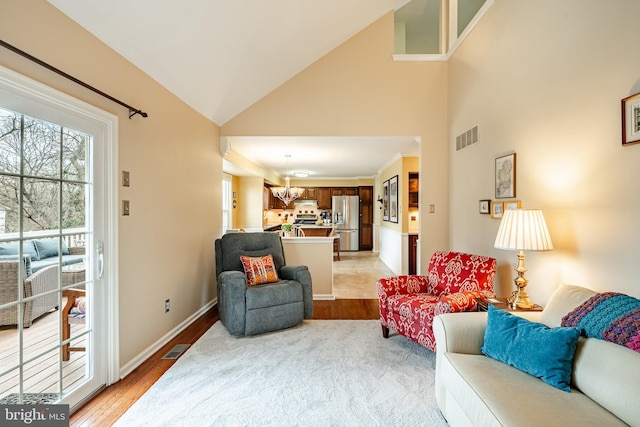 living room with visible vents, baseboards, high vaulted ceiling, and light wood finished floors