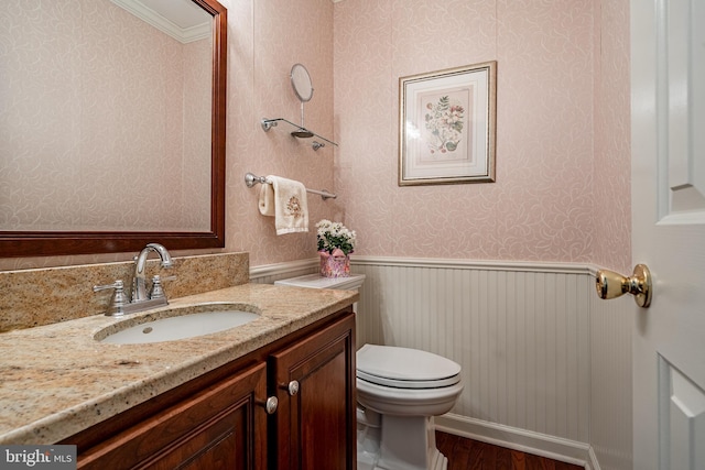 bathroom featuring a wainscoted wall, toilet, and wallpapered walls