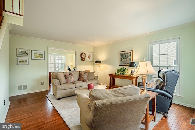 living room featuring hardwood / wood-style floors, crown molding, baseboards, and visible vents