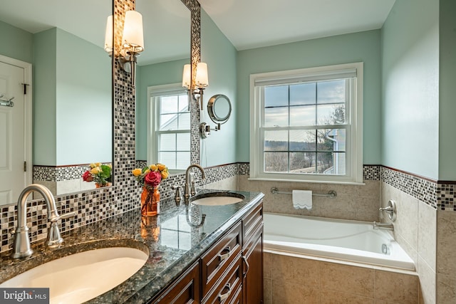 bathroom featuring a sink, a bath, and double vanity