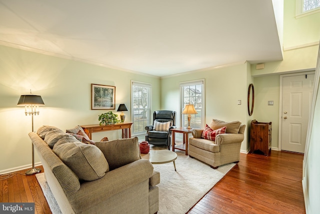 living area with baseboards, crown molding, and hardwood / wood-style flooring