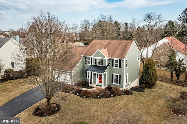 view of front of home featuring fence, a standing seam roof, a front lawn, aphalt driveway, and metal roof